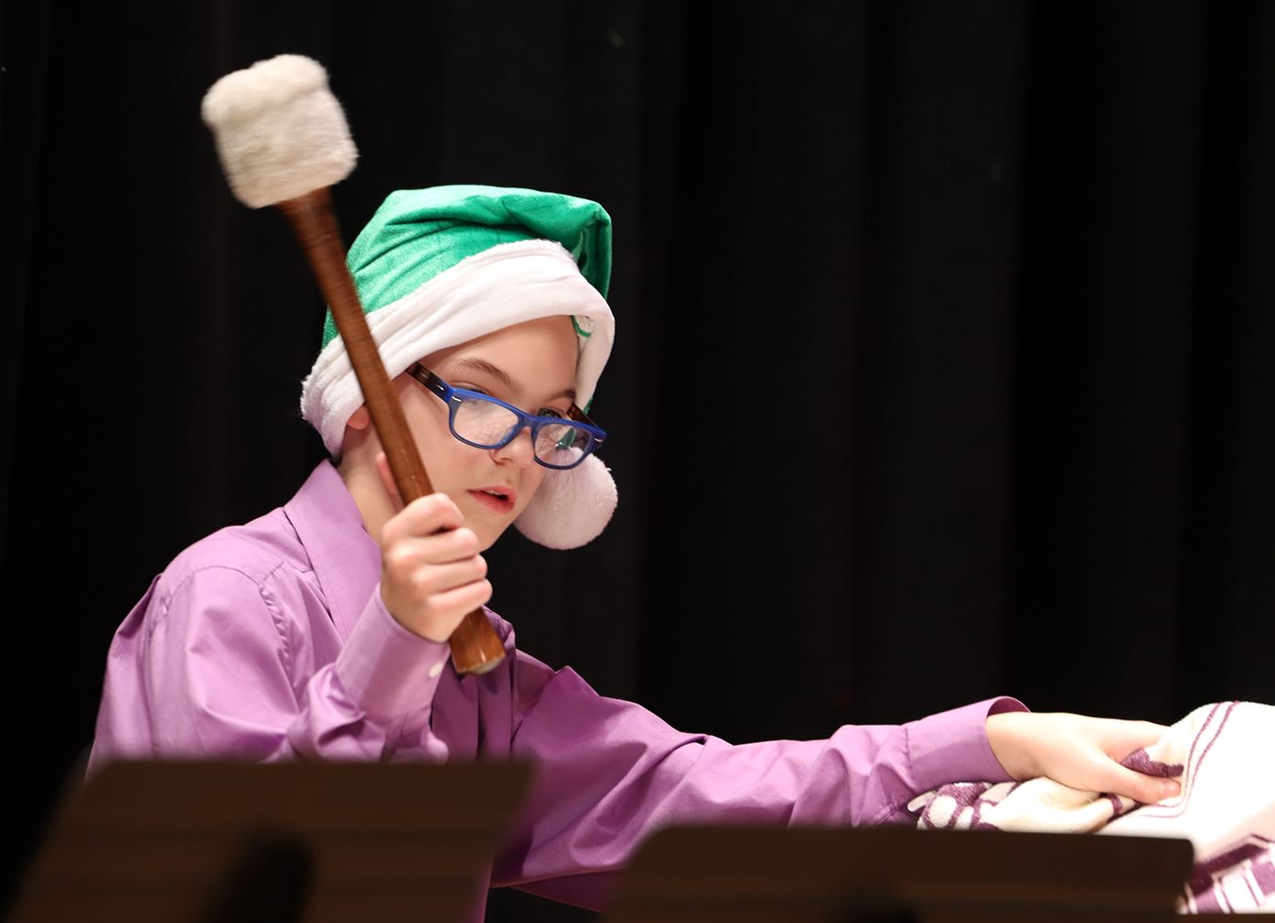  Decked out in a Santa hat, a Dennis M. Kenney Middle School student plays the drums.